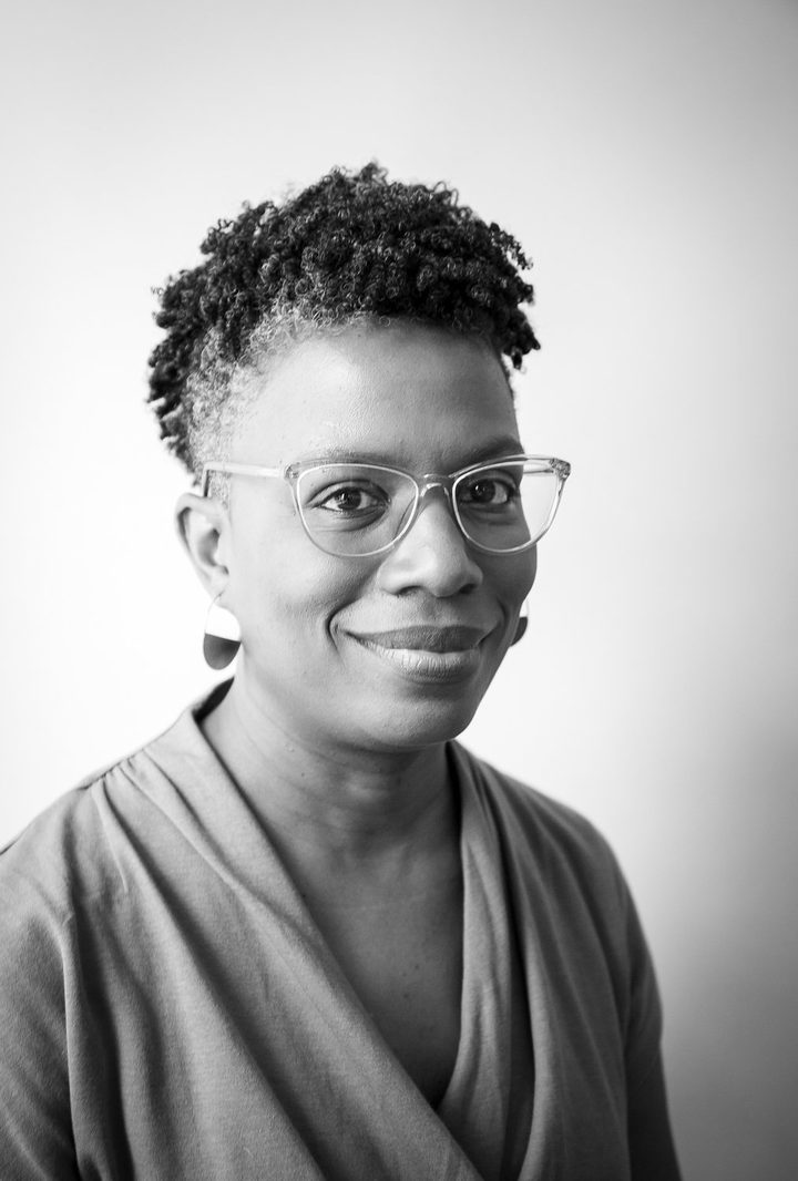 Angela Gorden, in clear-framed glasses, smiling.